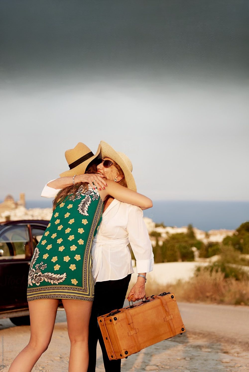 Two women hugging by a car